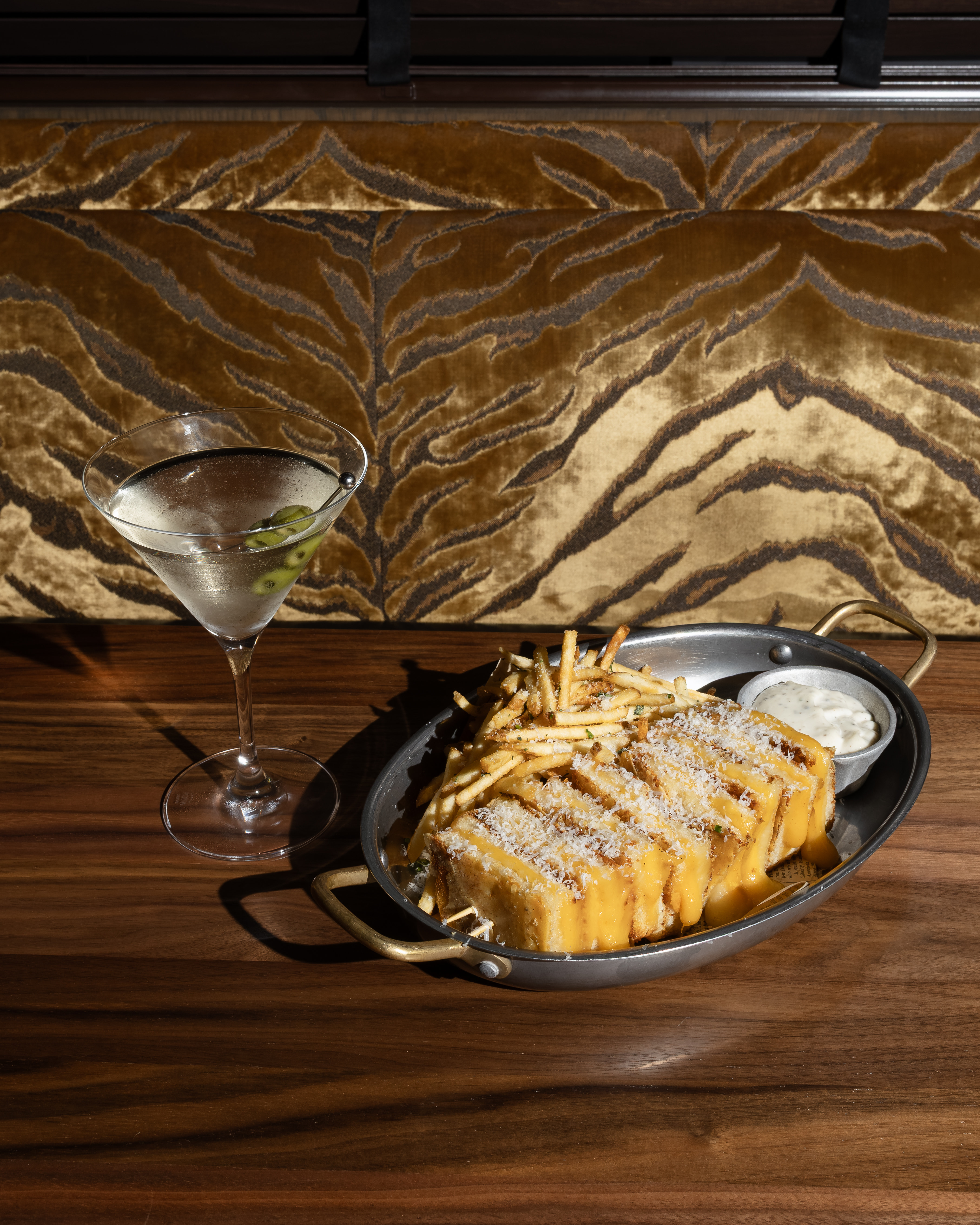 dirty martini with grilled cheese and fries on a dark wood table 